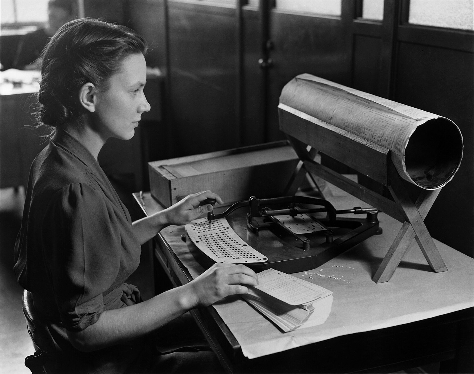 A woman seated at a Hollerith pantograph punch, a large keyboard-and-stylus machine, coding a card for the 1940 United States census.